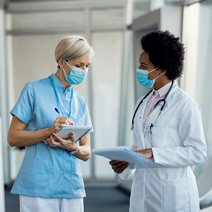 black-female-doctor-nurse-with-face-masks-communicating-hospital-hallway-rid iTrust app